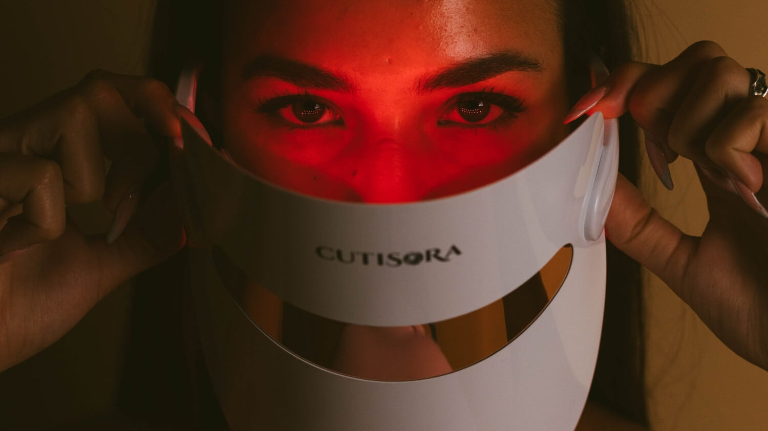 Жена, носеща LED маска за лице Lumina Glow от Cutisora с включена червена светлина, която подчертава модерния и ергономичен дизайн на маската.